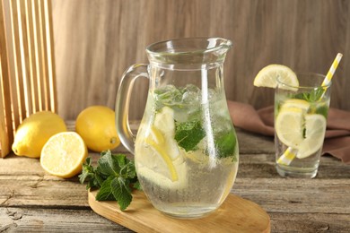 Refreshing lemonade with mint in jug and glass on wooden table