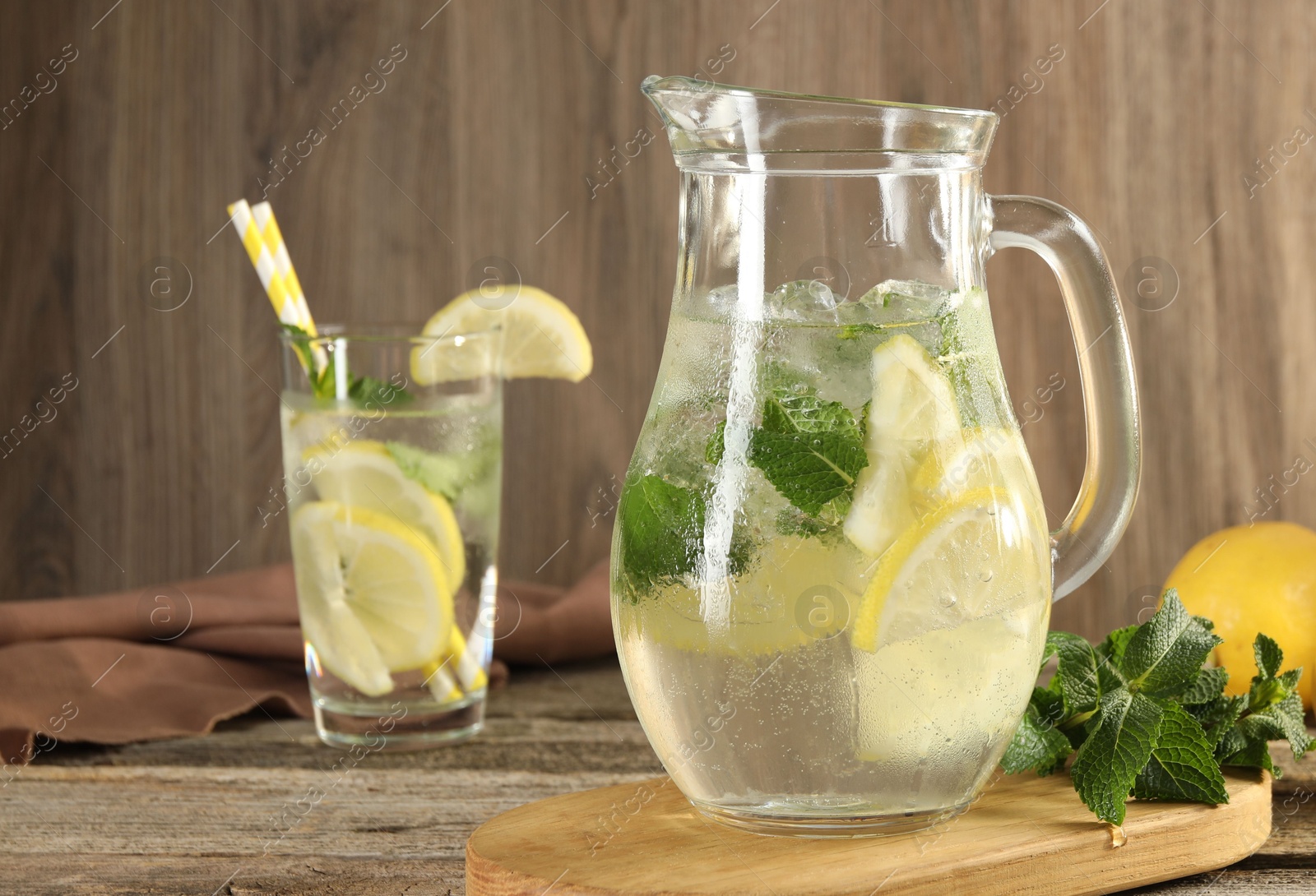 Photo of Refreshing lemonade with mint in jug and glass on wooden table