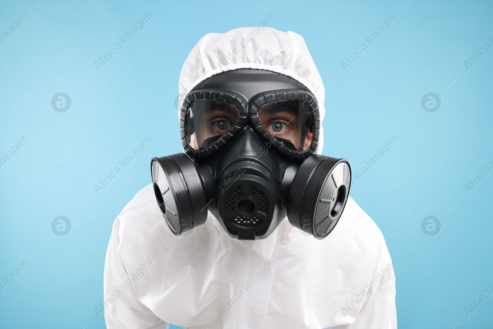 Photo of Worker in gas mask on light blue background