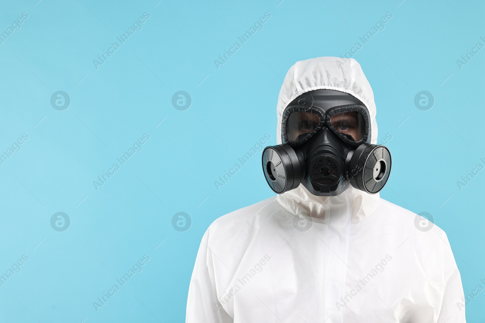 Photo of Worker in gas mask on light blue background. Space for text