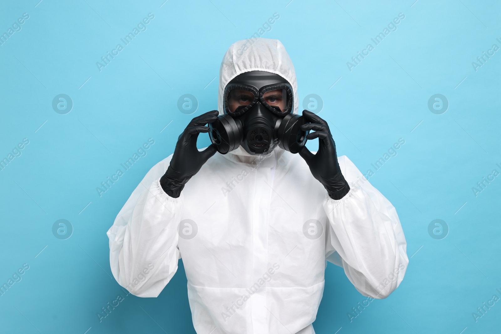 Photo of Worker in gas mask on light blue background