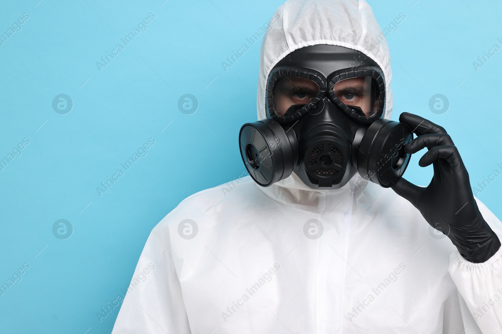 Photo of Worker in gas mask on light blue background. Space for text