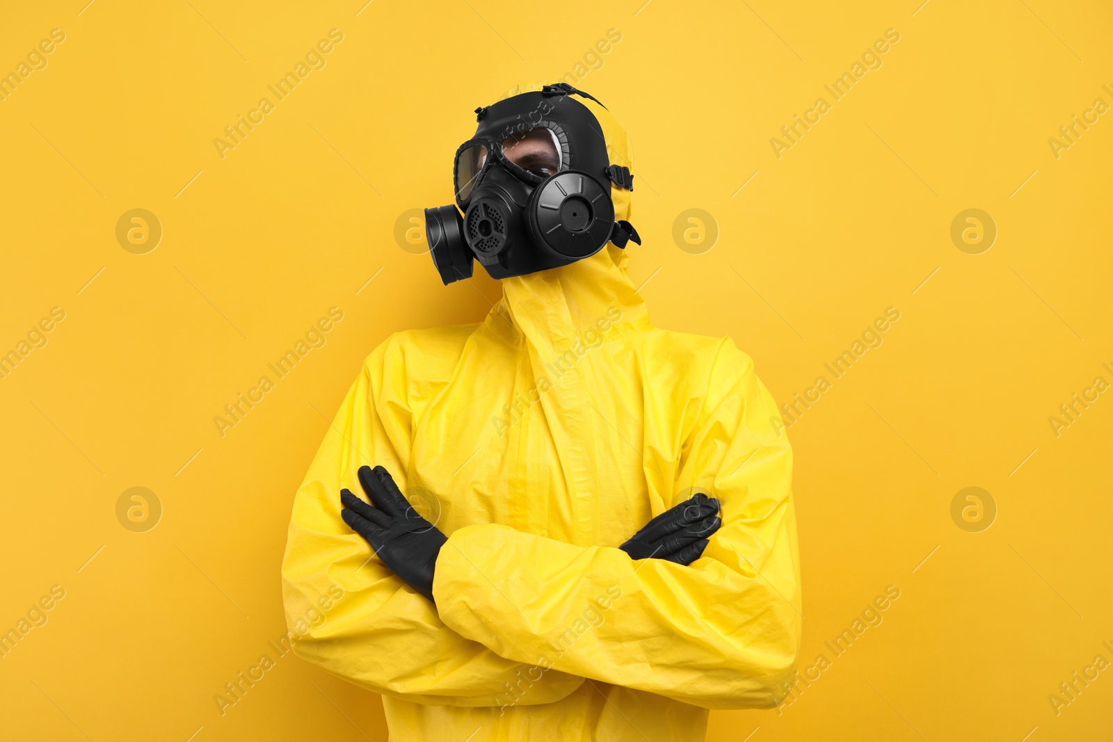 Photo of Worker in gas mask with crossed arms on yellow background