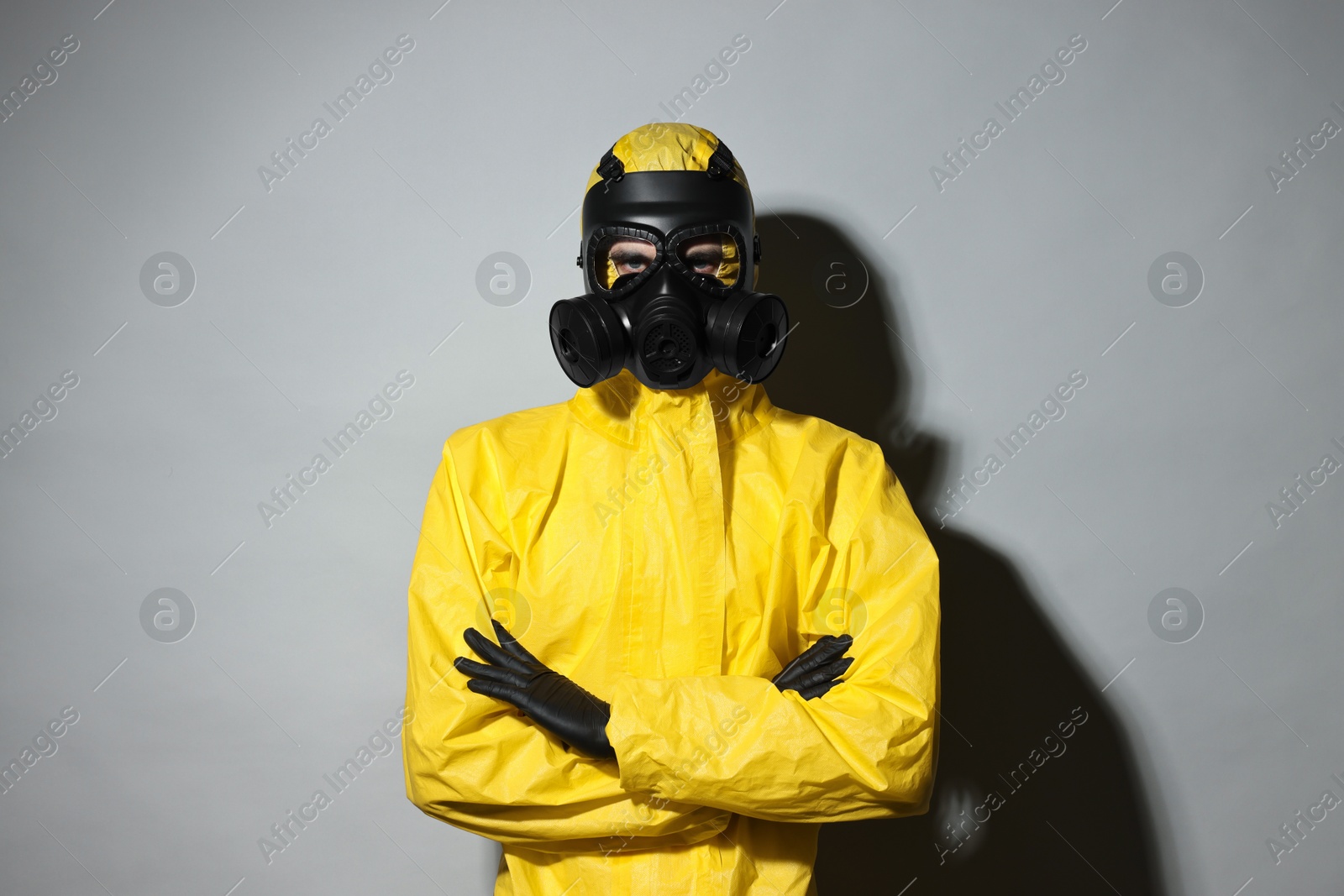Photo of Worker in gas mask with crossed arms on grey background