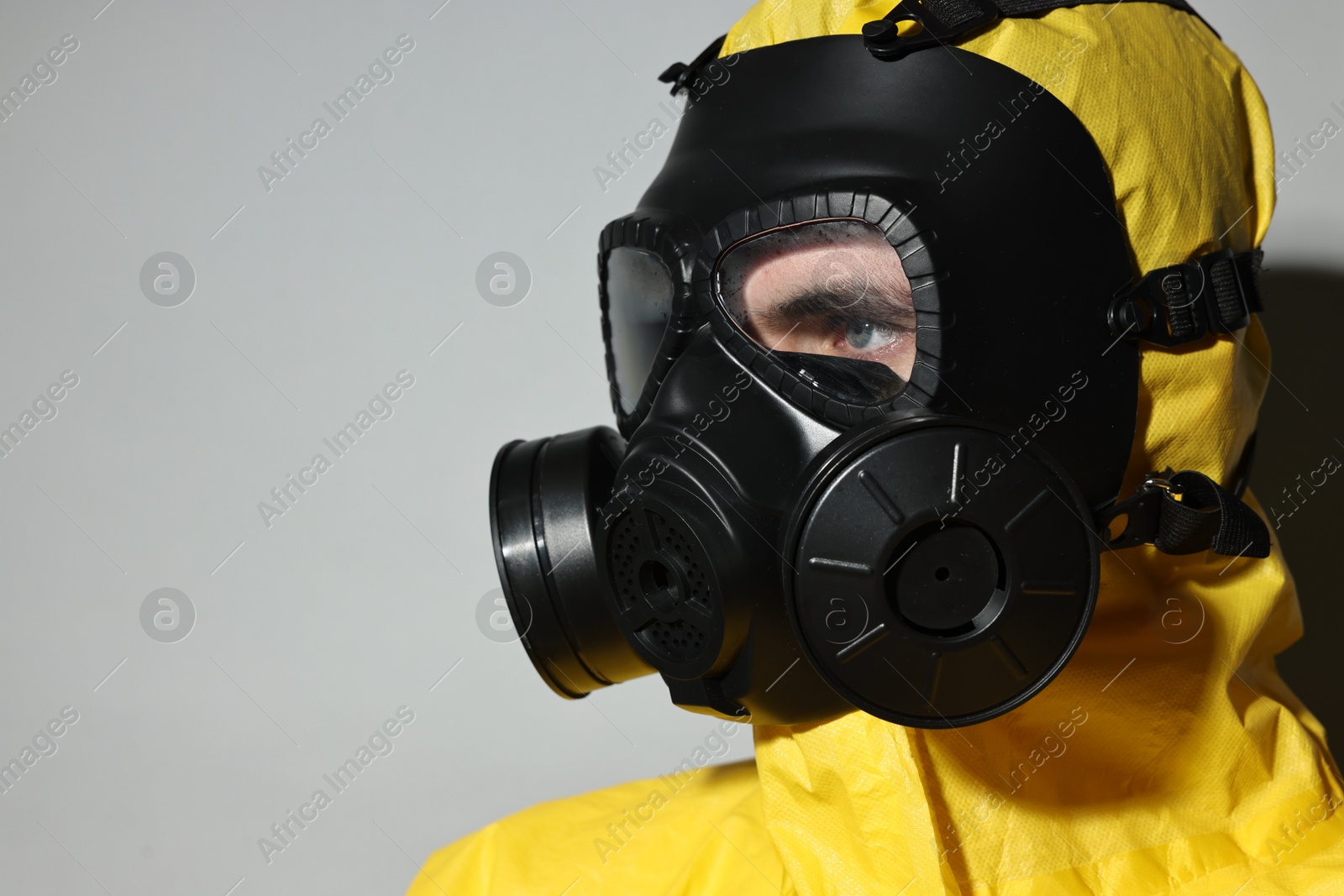 Photo of Worker in gas mask on grey background, closeup. Space for text