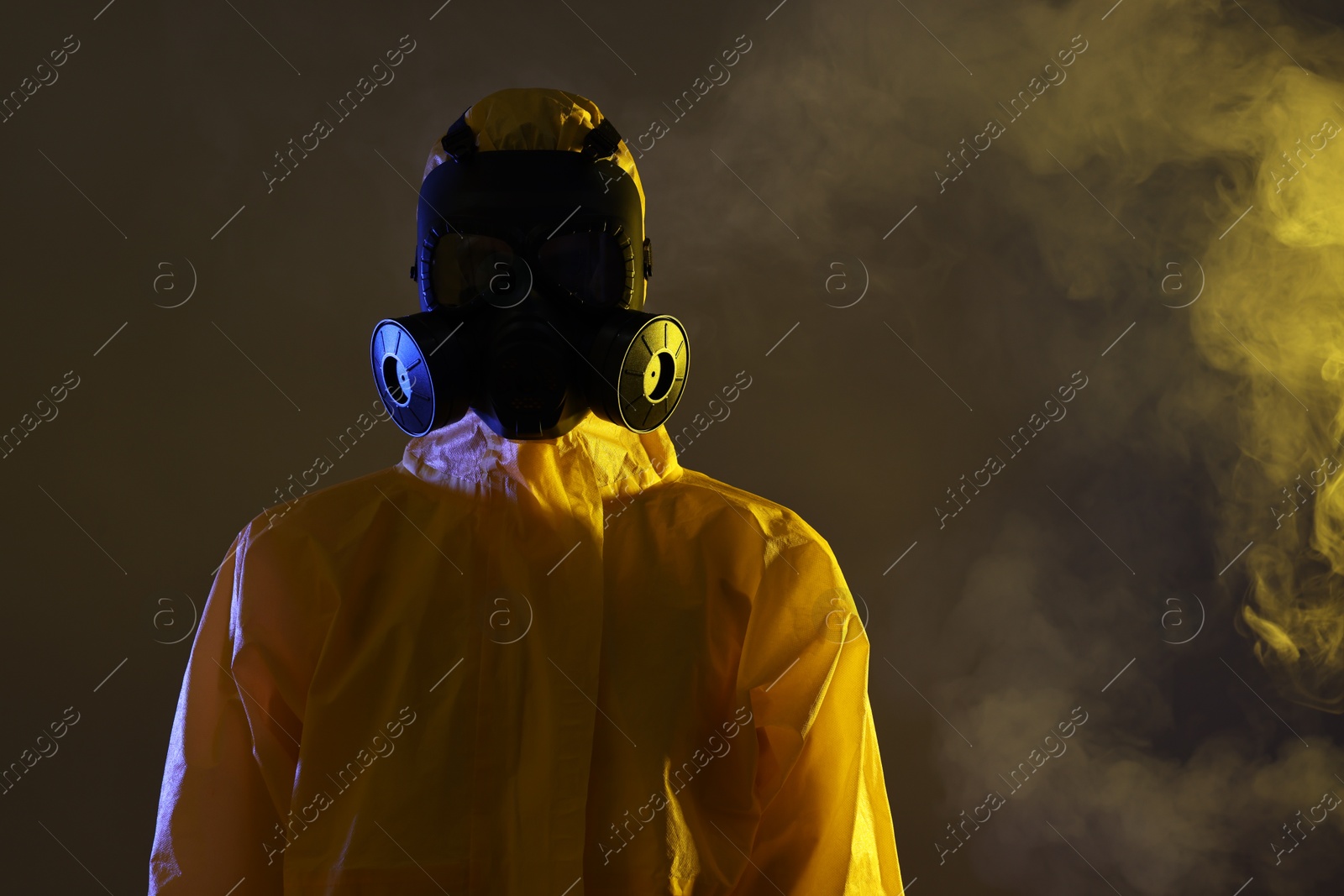 Photo of Worker wearing gas mask in smoke on dark background. Space for text