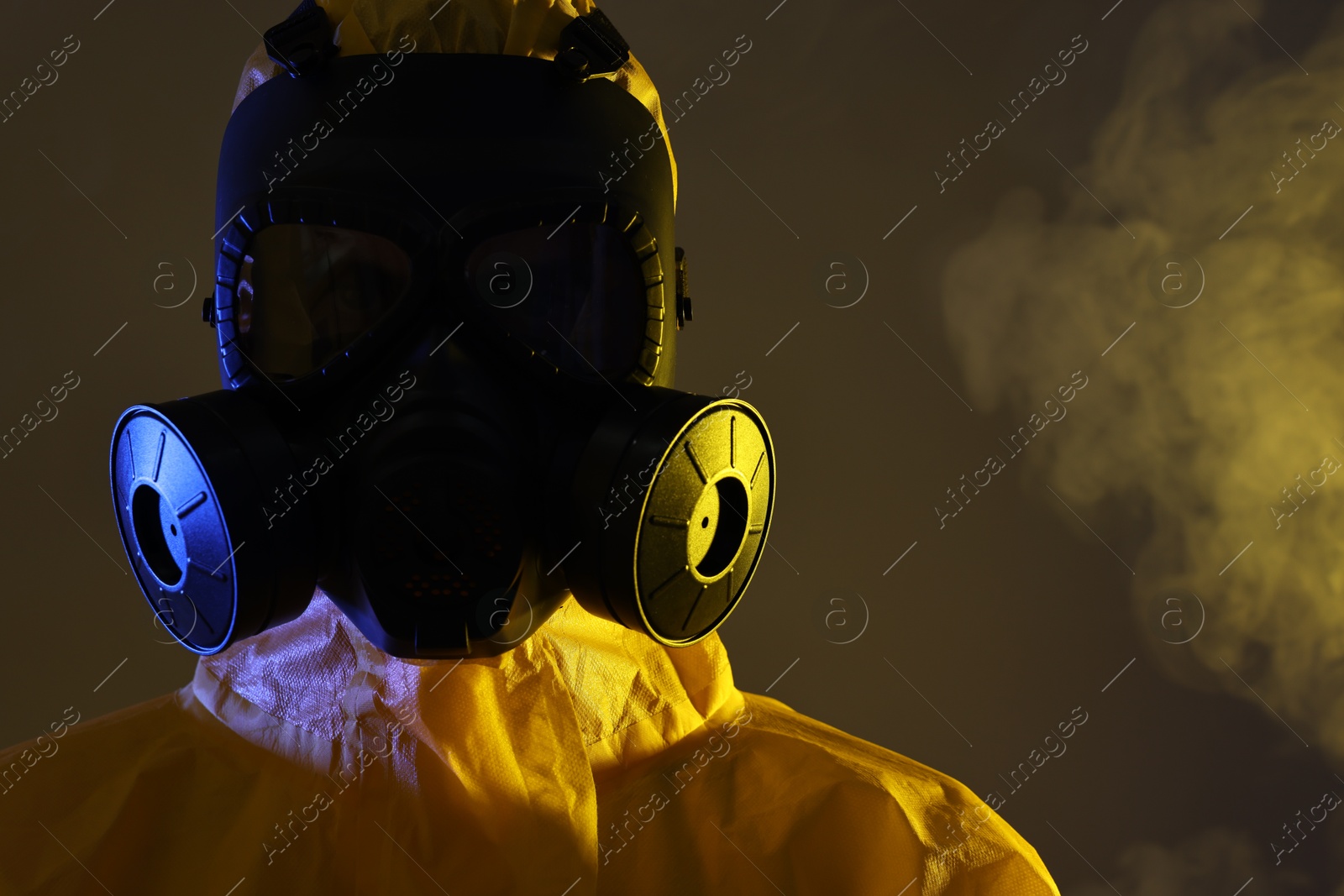 Photo of Worker wearing gas mask in smoke on dark background, closeup. Space for text