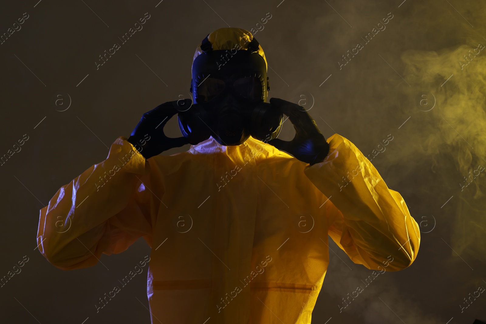 Photo of Worker wearing gas mask in smoke on dark background