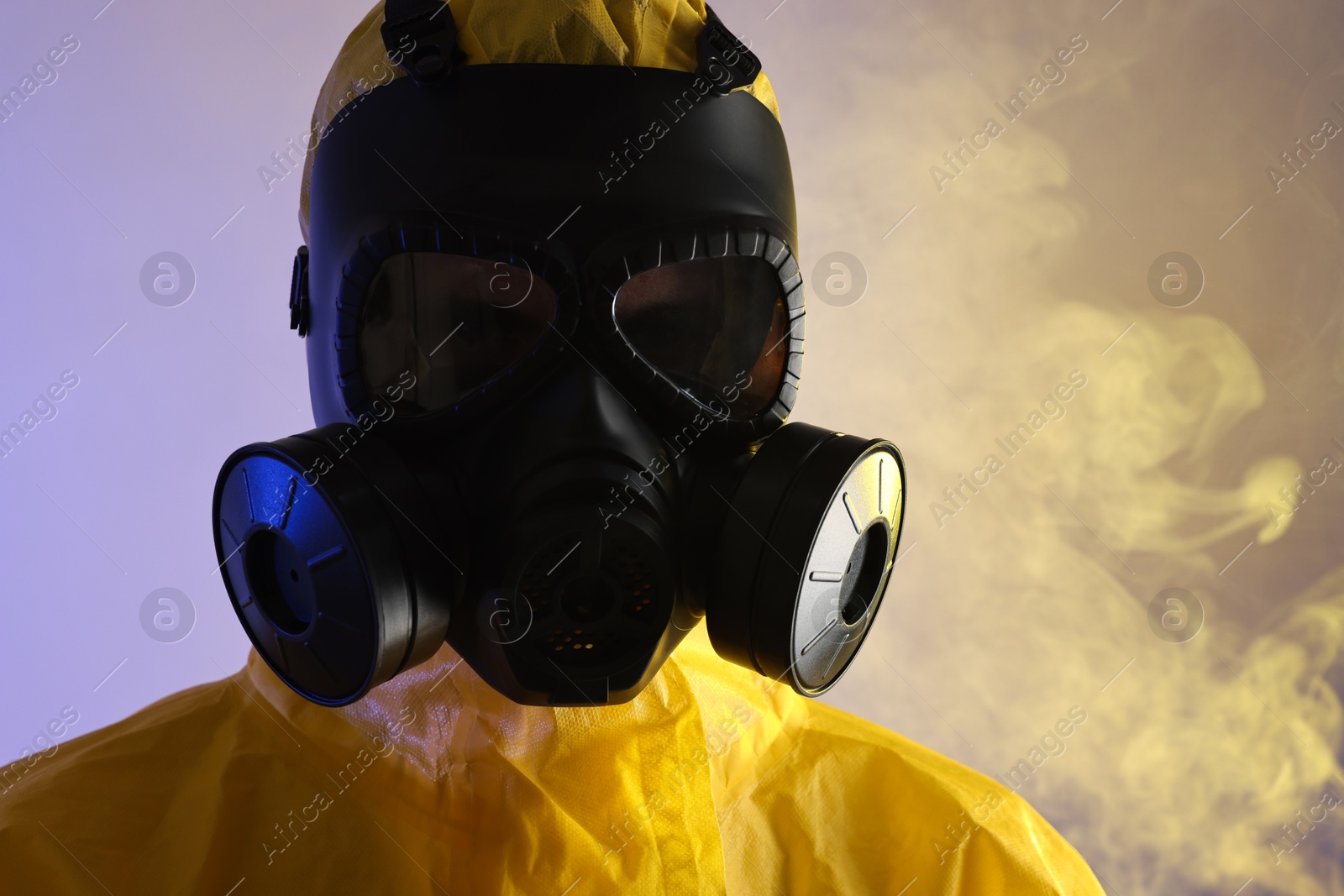 Photo of Worker wearing gas mask in smoke on violet background, closeup