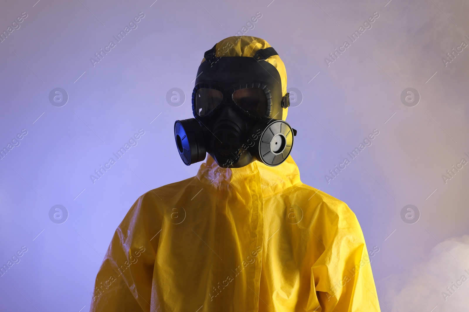 Photo of Worker wearing gas mask in smoke on violet background