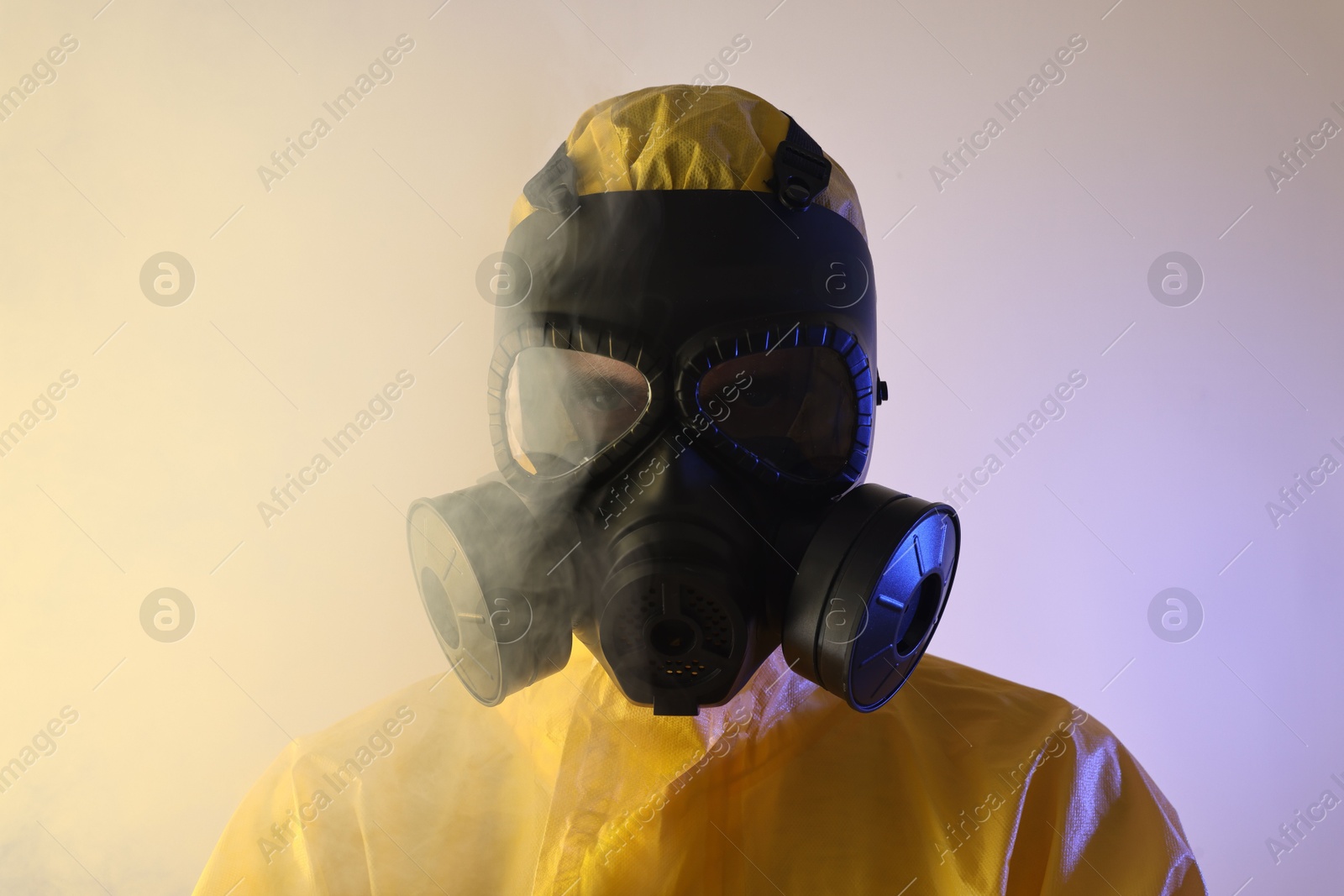 Photo of Worker wearing gas mask in color lights and smoke