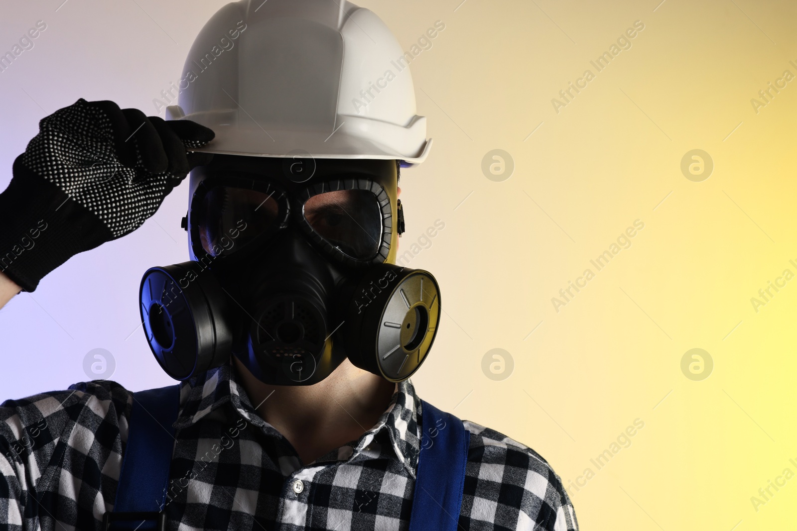 Photo of Worker in gas mask and helmet on color background. Space for text