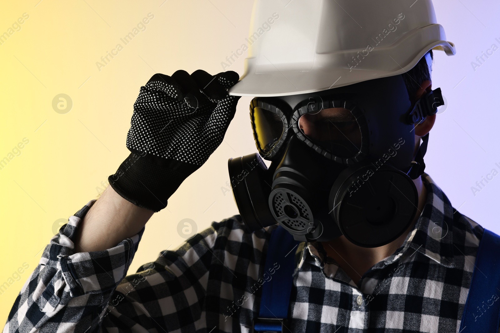Photo of Worker in gas mask and helmet on color background