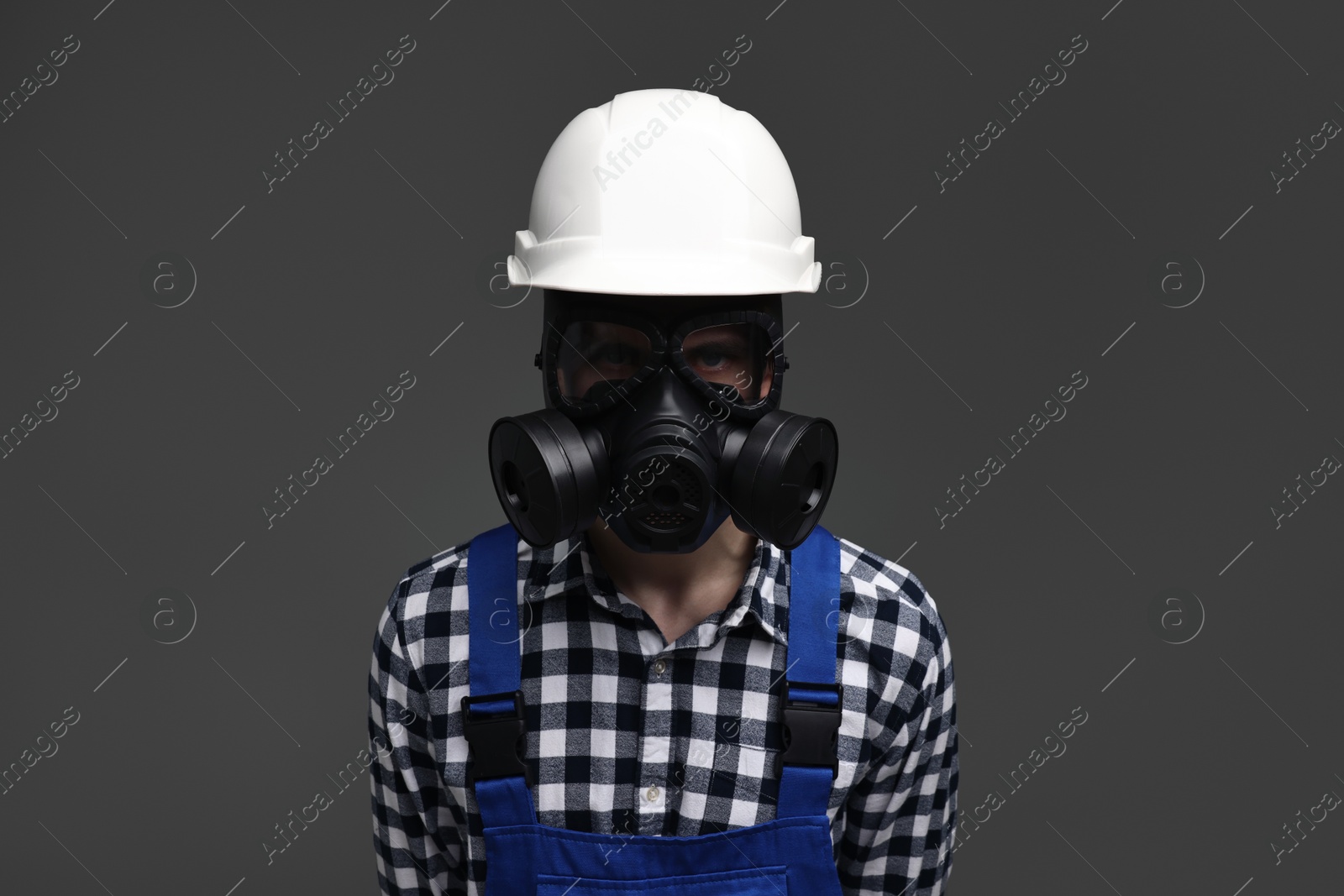 Photo of Worker in gas mask and helmet on grey background