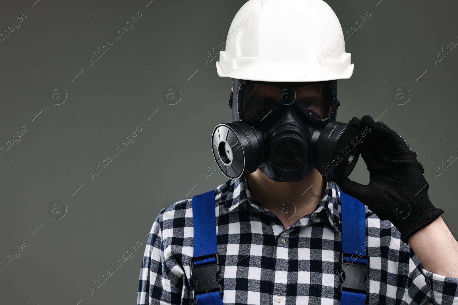 Photo of Worker in gas mask and helmet on grey background. Space for text
