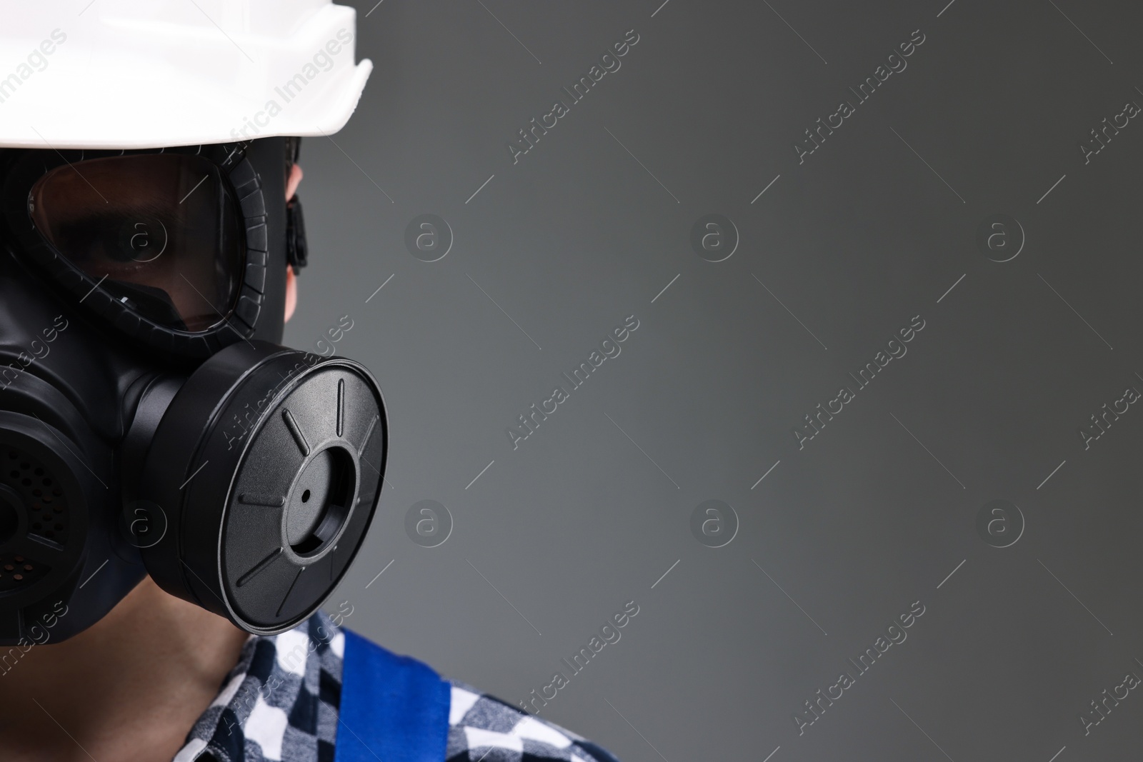 Photo of Worker in gas mask on grey background, closeup. Space for text