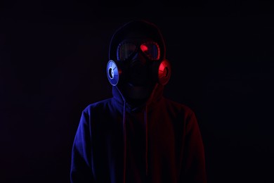 Photo of Man wearing gas mask in color lights on black background