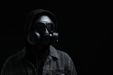 Photo of Man in gas mask on black background. Space for text