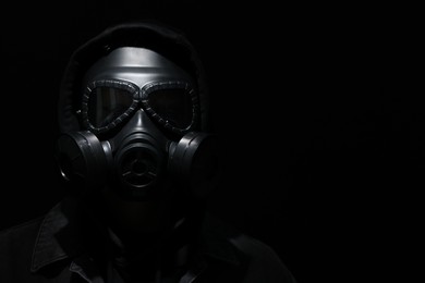 Photo of Man in gas mask on black background. Space for text