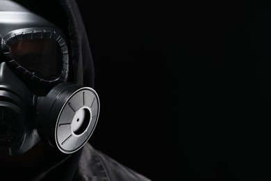Photo of Man in gas mask on black background, closeup. Space for text
