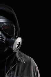 Man in gas mask on black background, closeup. Space for text