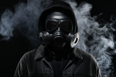 Photo of Man wearing gas mask in smoke on black background