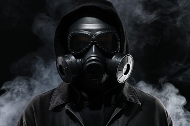 Man wearing gas mask in smoke on black background
