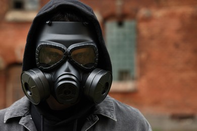 Photo of Man in gas mask near building outdoors. Space for text
