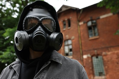 Photo of Man in gas mask near building outdoors, low angle view. Space for text