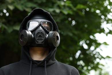 Photo of Man in gas mask outdoors, low angle view. Space for text