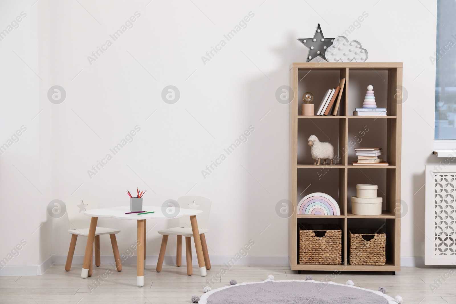 Photo of Child's room interior with wooden rack, table and chairs