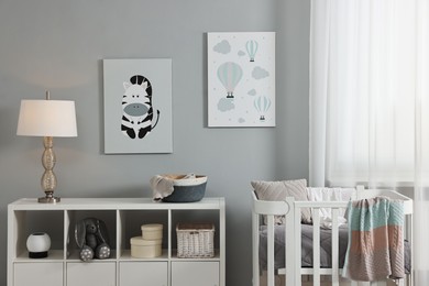 Photo of Newborn baby room interior with stylish furniture, comfortable crib and pictures of on wall