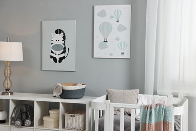 Newborn baby room interior with stylish furniture, comfortable crib and pictures of on wall