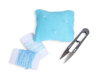 Photo of Light blue pincushion with sewing pins, cutter and threads isolated on white, top view