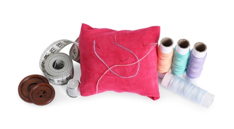Photo of Pincushion, sewing needles, spools of threads, measuring tape, thimble and buttons isolated on white