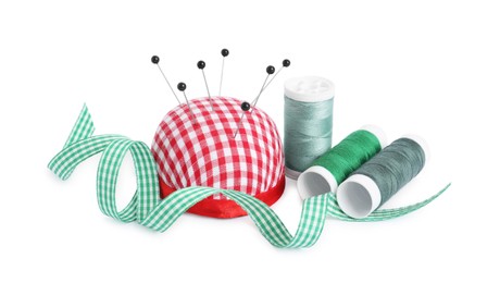 Photo of Pincushion, sewing pins, spools of threads and ribbon isolated on white