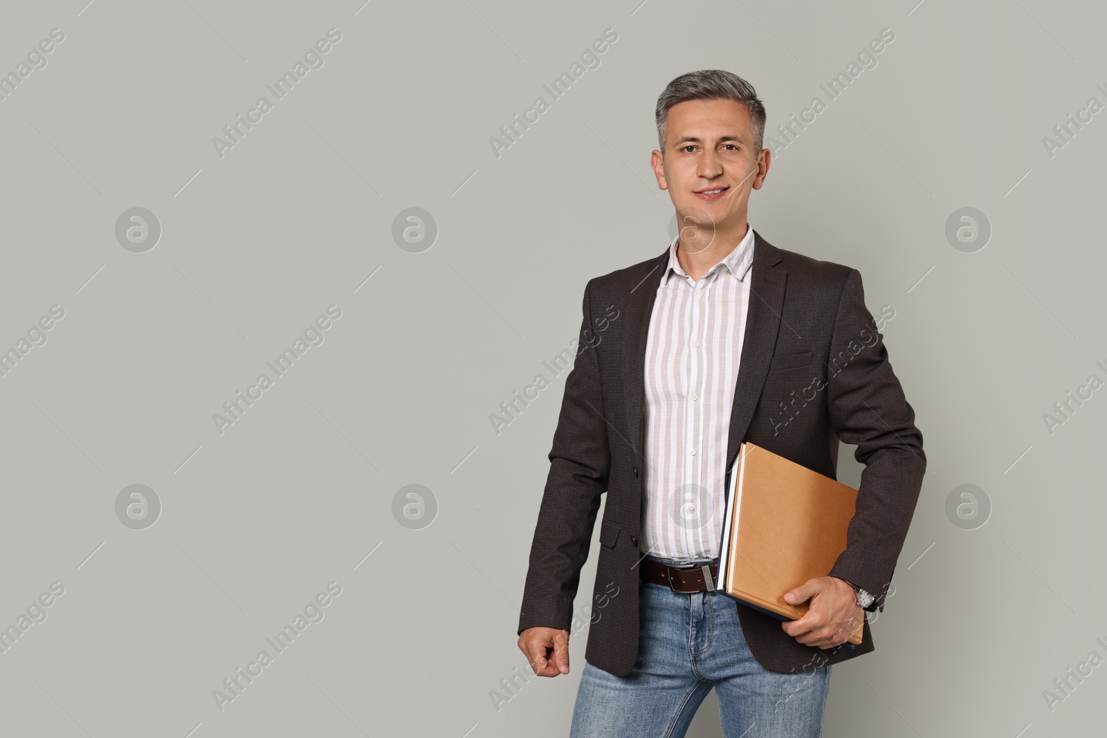 Photo of Happy teacher with notebooks on grey background, space for text