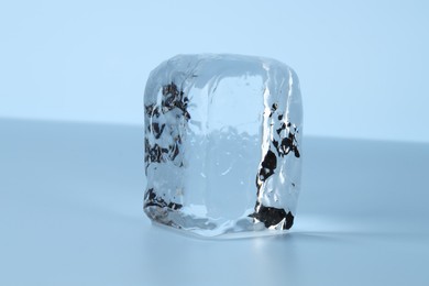 Cube of clear ice on light blue background