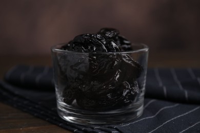 Tasty dried plums (prunes) in glass bowl on wooden table, closeup