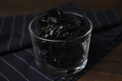 Tasty dried plums (prunes) in glass bowl on wooden table, closeup