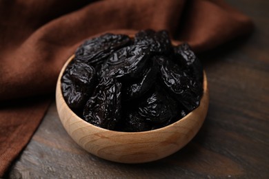 Photo of Tasty dried plums (prunes) in bowl on wooden table, closeup