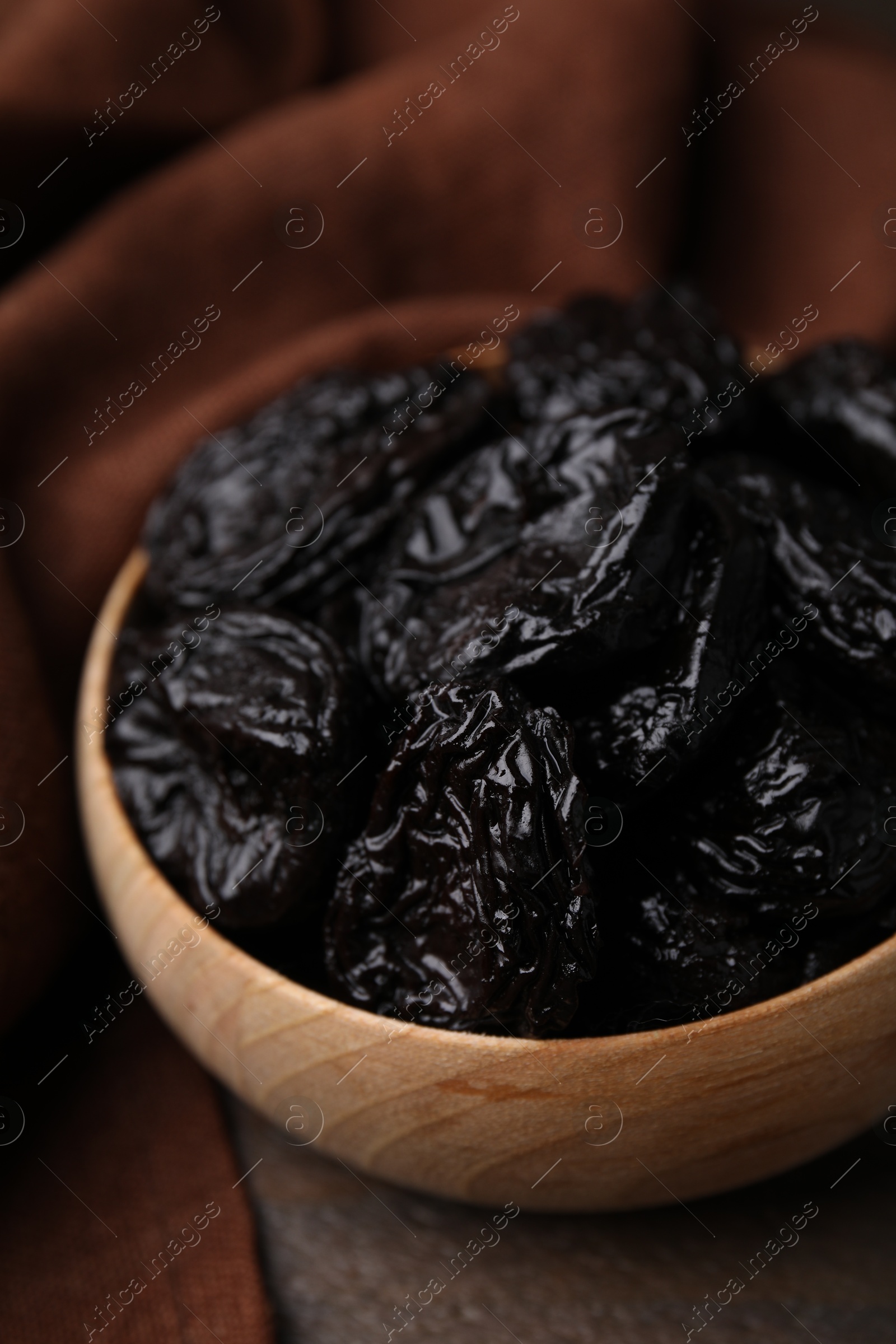 Photo of Tasty dried plums (prunes) in bowl on wooden table, closeup