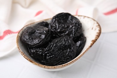 Photo of Tasty dried plums (prunes) on white tiled table, closeup