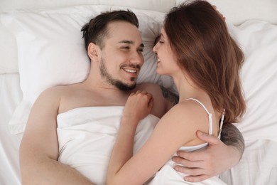 Photo of Lovely couple enjoying time together in bed at morning, top view