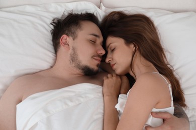 Lovely couple sleeping together in bed at home, top view