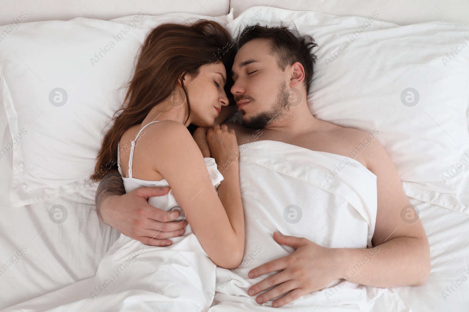 Photo of Lovely couple sleeping together in bed at home, top view