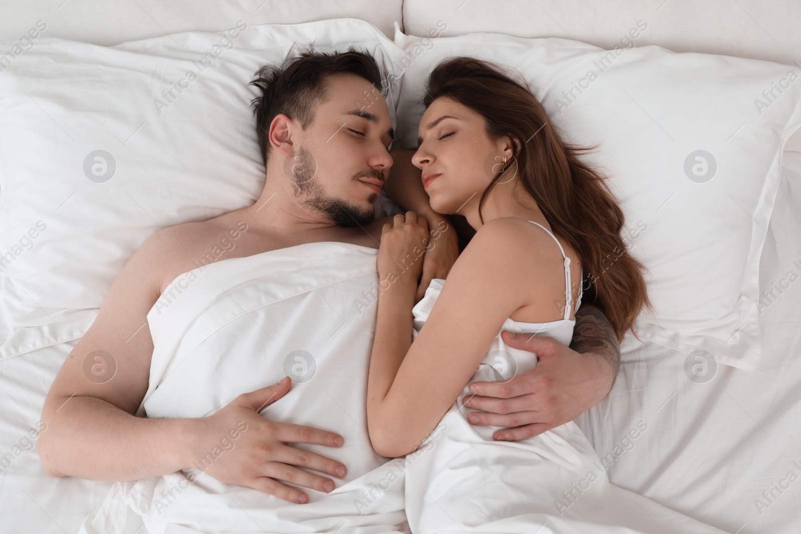 Photo of Lovely couple sleeping together in bed at home, top view