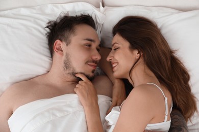 Photo of Lovely couple enjoying time together in bed at morning, top view