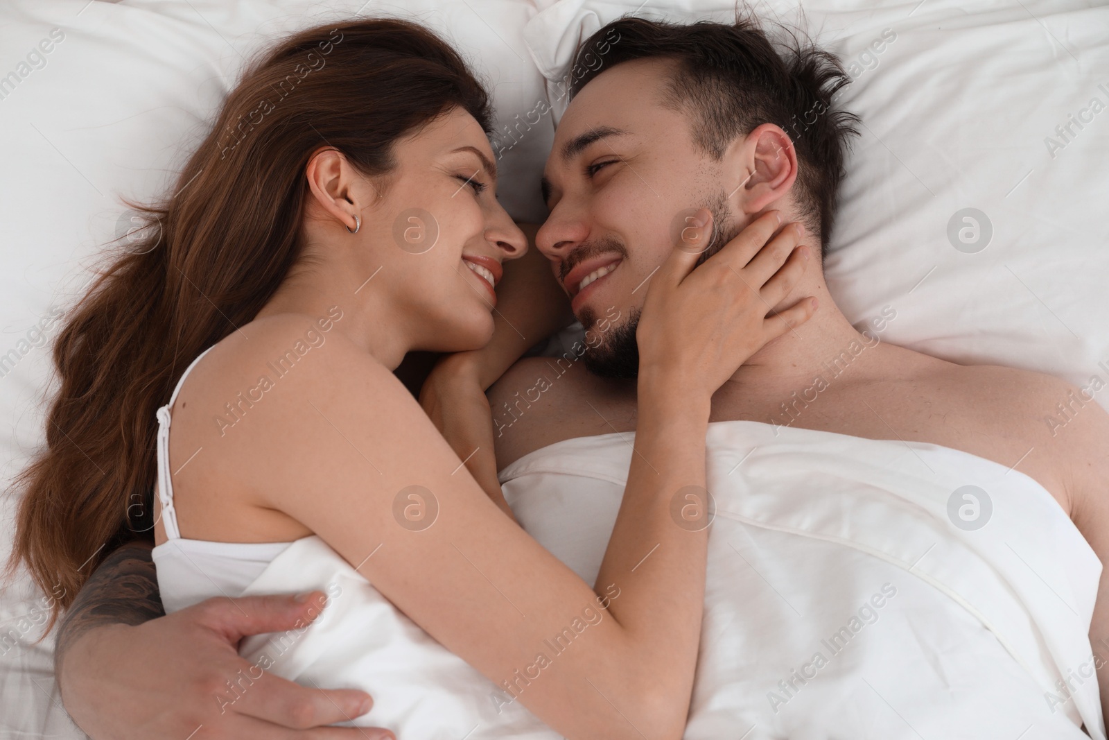 Photo of Lovely couple enjoying time together in bed at morning, top view