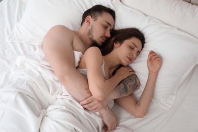 Lovely couple sleeping together in bed at home, top view